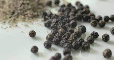 Siyah biber ve beyaz tabakta bütün biber, sağlıklı yemek pişirmede kullanmak için bir yığın içinde..