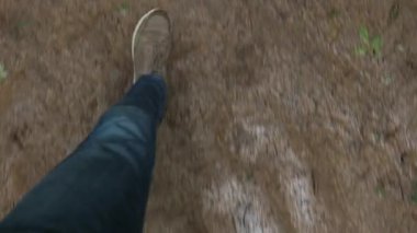 Çamurlu bir orman yolunda yürüyüş yapan ayak görüntüsü