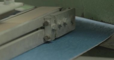 Büyük bir zımpara kağıdı fabrikada montaj bandından aşağı doğru hareket ederek daha küçük parçalara bölünür.