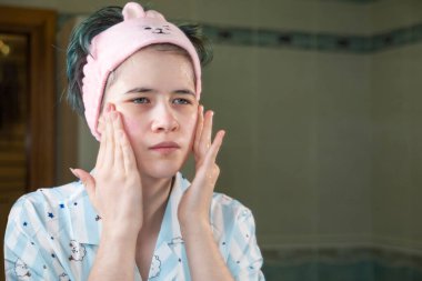 Kız cilt bakımı için kozmetik serumu kullanıyor. Derinin sağlığını ve güzelliğini önemser..