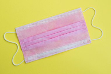 Sarı arka planda pembe tıbbi maske..