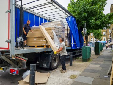 Londra mı? UK- 08.13.2021: Ağır yük araçlarından ağır paketleri boşaltan işçiler.