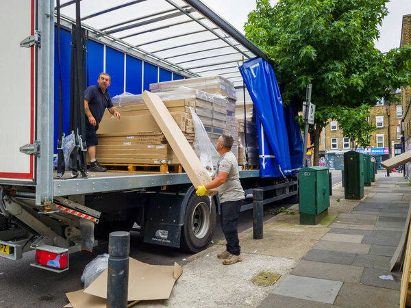 В Лондон. УК-08.13.2021: рабочие разгружают тяжелые грузы с грузового автомобиля.