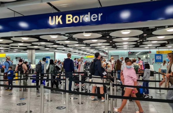 Heathrow Havaalanı. UK- 08.08.2021: Terminal 5 'teki Birleşik Krallık Sınır Çizgisi' nde göçmen kontrolü ve pasaport kontrolü için bekleyen seyahat yolcuları.