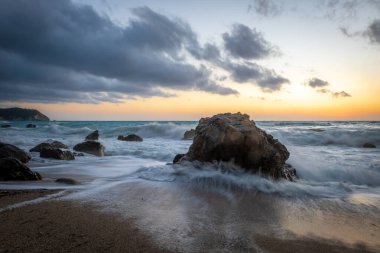 Sahilde dalgaların çekildiği bir sahil gün batımı..