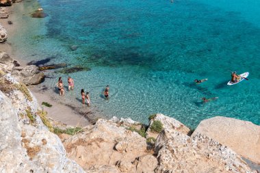 Lefkada adası. Yunanistan - 08.05.2021: Tatilciler berrak denizde güneşleniyor ve yüzüyorlar.