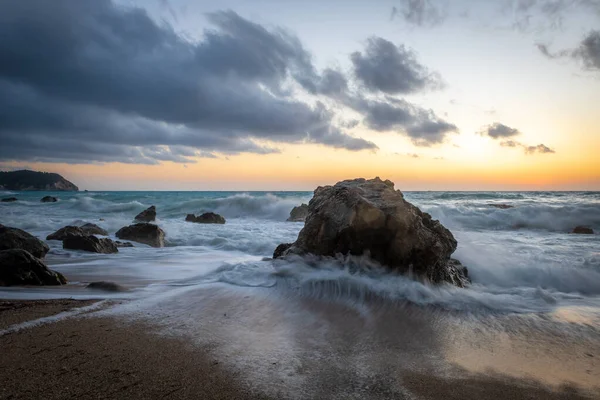 Sahilde dalgaların çekildiği bir sahil gün batımı..