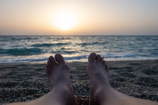 Kumsalda uzanmış güneşin batışını izleyen bir turist..