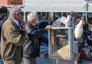Lefkada. Yunanistan. 10.28.2021. Patlamış mısır ve pamuk şeker satan yaşlı bir tezgahtar..