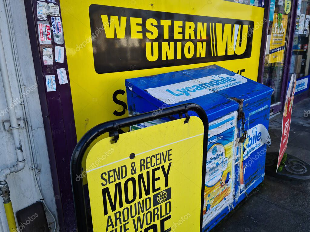 London. UK-01.31.2021. Western Union money transfer services advertising signs outside a corner shop.