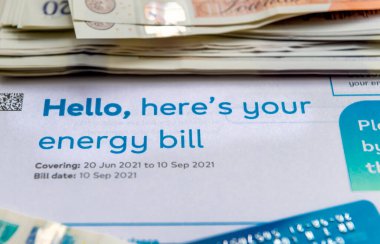 İçinde banknotlar ve ödeme kartı olan bir enerji faturası. Enerji maliyeti kavramı.
