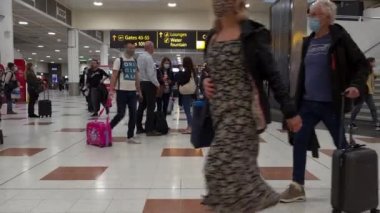 Gatwick Havaalanı. UK- 10.10.2021. Bir grup yolcu kalkış salonundaki uçuşlarını bekliyorlar ya da gidiyorlar..