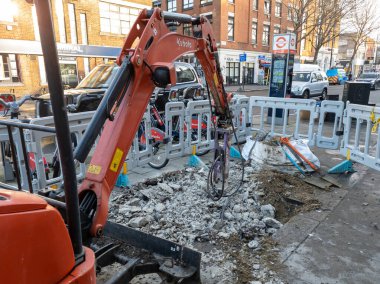 Londra mı? Birleşik Krallık-01.13.2022. Yaya kaldırımında yol onarımında kullanılan bir mekanik kazıcı. Yol onarımları.