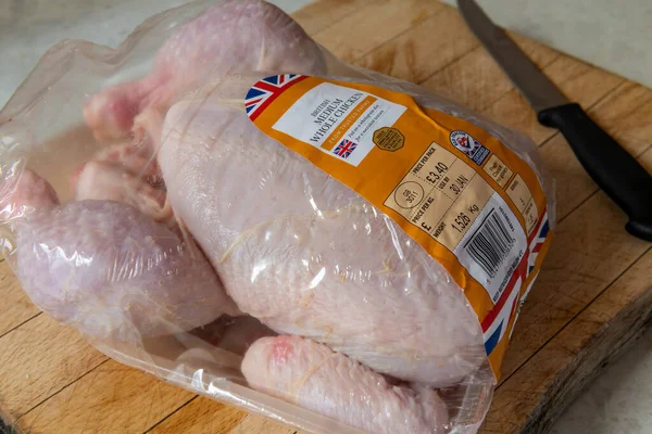 Marketten paketlenmiş bir tavuk kesme tahtasının üzerinde..