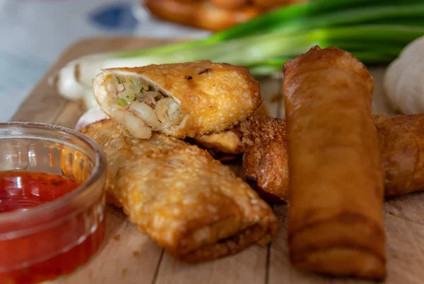 Tahta bir tahtanın üzerinde yeşil soğan ve sos ile çıtır çıtır altın yumurtalar..