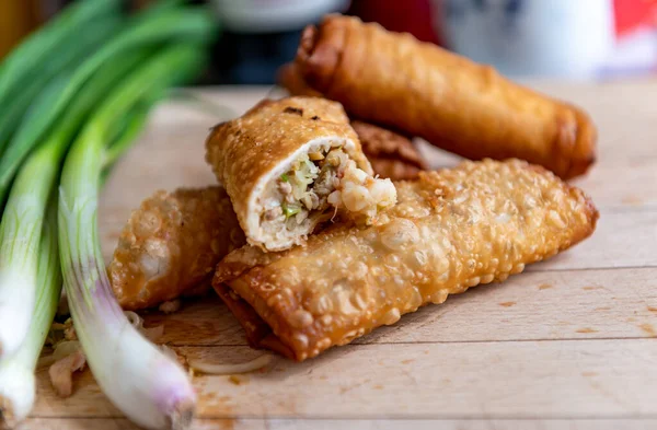 Yarısı doğranmış ve taze soğan servis etmeye hazır ahşap bir tahtanın üzerinde çıtır çıtır börekler..