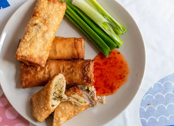 Taze soğanlı ve Tayland biberli bir tabakta servis edilen tam ve kıtır kıtır kızarmış börek..