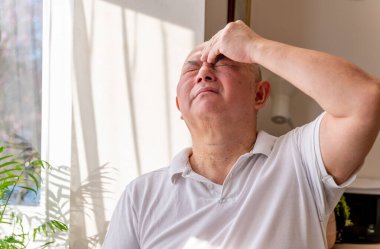 Evde kendini kötü ve acı içinde hissederek çimdikleyen ve başını ovuşturan olgun bir son sınıf öğrencisi. Kötü konsept..