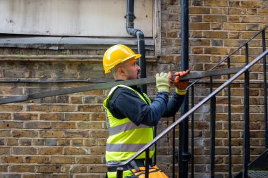 İnşaat alanında çalışan bir inşaat işçisi omzunda metal bir çubuk taşıyor..