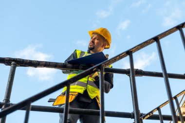 Bir bina ustabaşı not alıyor ve inşaat çalışmalarını denetliyor..