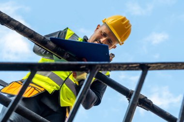 Bir bina ustabaşı not alıyor ve inşaat çalışmalarını denetliyor..