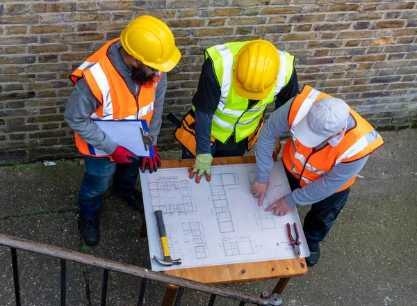 İnşaat planına sahip mimar inşaat şefleriyle görüşüyor..