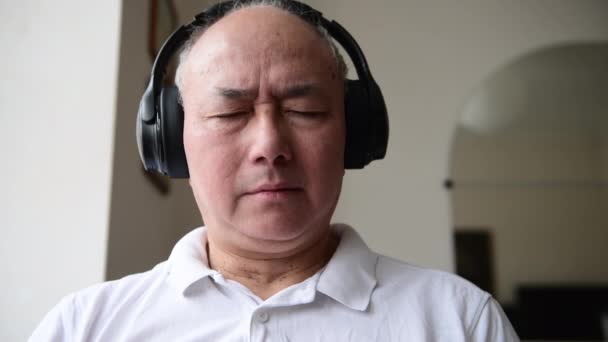 一位老年人在家里用无线耳机放松地听音乐 — 图库视频影像
