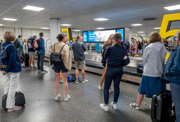 Gatwick Havaalanı, UK-06.08.2022. Uçak yolcuları Kuzey Terminalinden bavullarını almak için bekliyorlar..