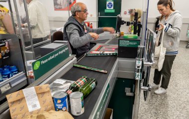 Londra mı? UK- 06.19.2022. Bir süpermarkette müşterinin alışverişini bir çantaya koyması..
