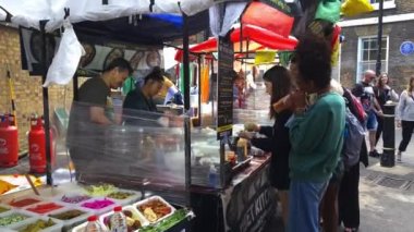 Londra mı? Birleşik Krallık-06.26.2022. Brick Lane Market 'te büyük bir turist ve ziyaretçi kalabalığı sokak yiyecek dükkanlarını ziyaret ediyor..