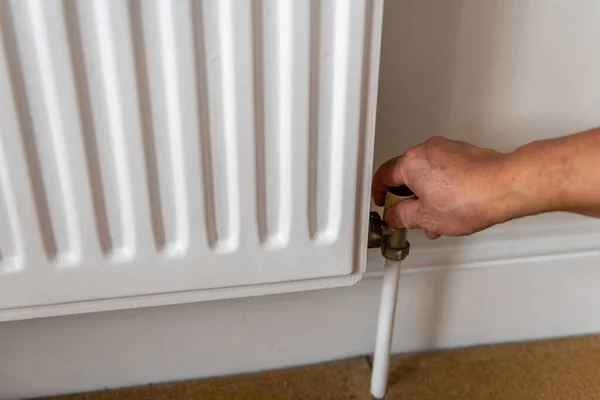 A person turning off the heating radiator to safe on energy cost.