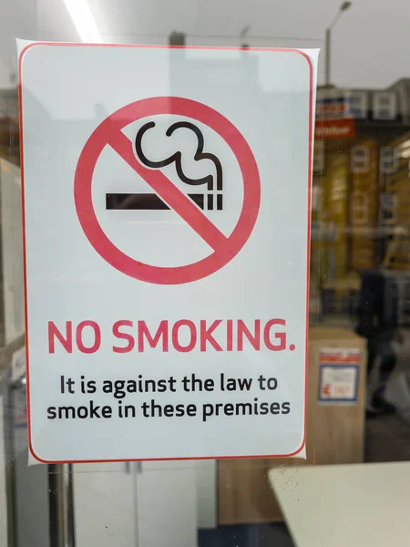 A no smoking sign in the window of a retail store.