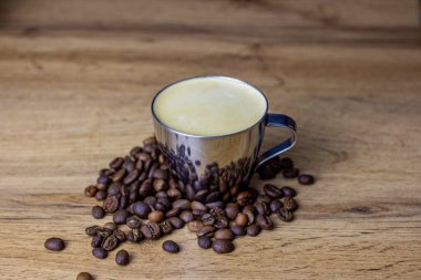 Taze kahveyle metal bardak. Kahve çekirdekleri masada.