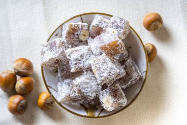 İçinde Türk Lokumu ve arkaplanda nane aromalı siyah çay bulunan bir kase. Doğulu tatlılar.