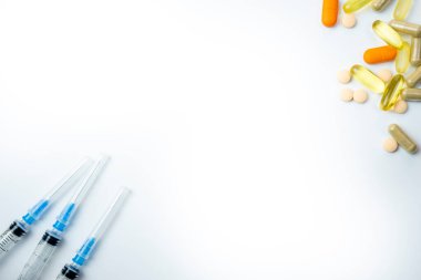 Tıbbi şırınga beyaz arka planda farklı haplarla izole edilmiş.