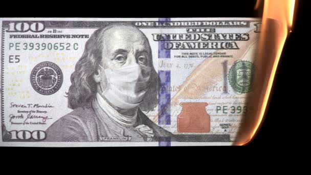 One hundred usd dollar bill with protective medical mask on Benjamin Franklin portrait burning from fire. Economic Crisis during Covid-19 Pandemic concept. 100 dollar banknote. 4k high quality video — Stock Video