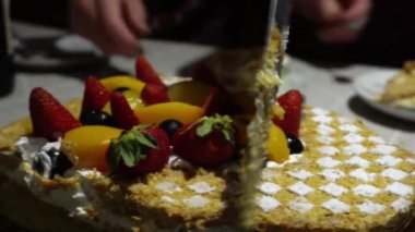 4K doğumgününde bıçak ve spatula kullanarak çilekli ve şeftalili bir Milhojas pastası kesiyorum.