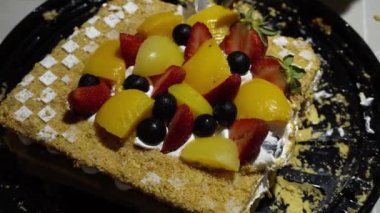 Yakın plan Milhojas pastasını çilek, şeftali, çekiç ve üzümle keserken 4K 'da doğum günü için bıçak ve spatula kullanın.