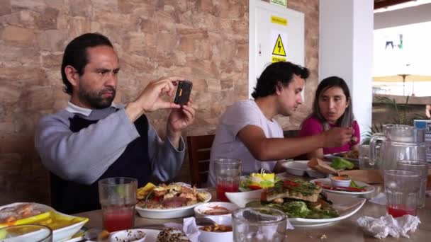 Egy Férfi Aki Ételeket Mobiljával Rögzíti Egy Családi Összejövetelen Egy — Stock videók