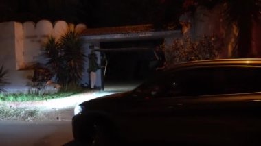 İki arkadaş bir kır evinin kapısını tutuyorlar. Bir arabanın içeri girmesi ve gece karşılaması için.