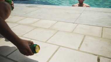 Bira kutusunu yere yuvarlayıp havuzda bir adamın ağzına atıyordu.