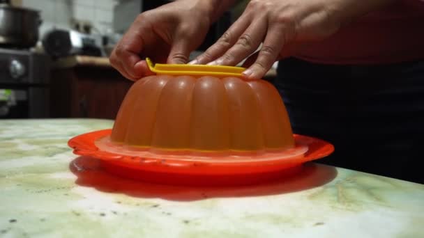 Zbliżenie Biorąc Pomarańczowy Galaretka Pleśń Rękami Stole Kuchnia — Wideo stockowe