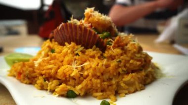 4K 'da plajdaki bir restoranda deniz mahsullü bir pirinç yemeğinin yakın çekimi.