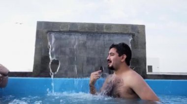 4K 'da bir sahil evinde şelale arasında havuzda tartışan bir çift.