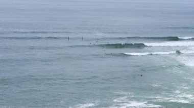 Gün içinde dalgalar ve martılarla denizde birkaç sörfçü ve kürekçi.