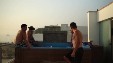 Sahile bakan bir evde, gün batımında havuzun kenarında oturan birkaç arkadaşla birlikte bir yüzme havuzuna giriyoruz.