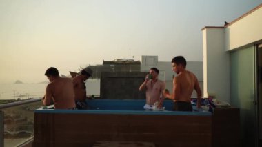 Birkaç arkadaş gün batımında sahile bakan bir evin havuzunda bira içip kadeh kaldırıyor.