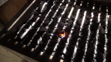 Geceleri ızgaranın içinde kömürlerin arasında yanan bir çakmağın yakın çekimi.