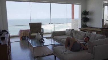 Odadaki büyük bir koltukta yatan bir adam bakıyor. Gün içinde bir sahil evinde deniz manzaralı güzel bir yerde dinlenme ve dinlenme.