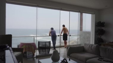 Denize bakan ve bulutlu bir günde bir sahil evinin terasında konuşan iki arkadaş.